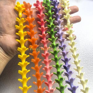 May include: Six strands of colorful plastic beads, each featuring a repeating branch-like or floral shape. The strands are yellow, orange, pink, green, purple, and cream. The text Amyjewelry1012 is visible in the center of the image.