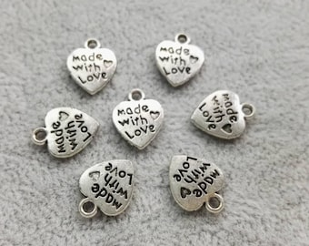 May include: Seven silver-toned metal heart-shaped charms, each featuring a small loop at the top for attachment. The surface of every charm is embossed with the text "made with Love" and a small heart symbol in a dark, recessed font.