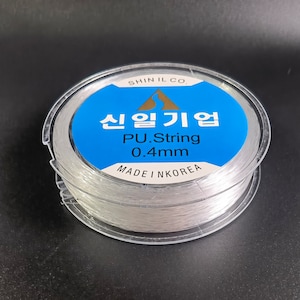 May include: A spool of clear, white, 0.4mm PU string, labeled "Shin Il Co.  신일기업 PU.String 0.4mm Made in Korea"
