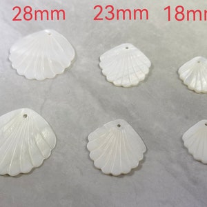 Könnte beinhalten: Sechs weiße Perlmutt-Muschel Anhänger in verschiedenen Größen. Die Muscheln sind in Form einer Jakobsmuschel geformt und haben oben ein Loch zum Aufhängen. Die Muscheln sind 28 mm, 23 mm und 18 mm groß.