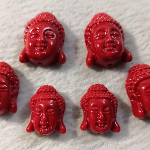 Puede incluir: Seis cuentas de cabeza de Buda rojas, cada una con una cara y un cabello detallados, perfectas para hacer joyas o manualidades.
