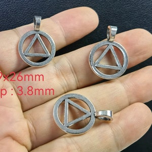 May include: Three silver metal pendants with a circle design and a triangle inside. The pendants measure 19 x 26 mm with a 3.8 mm loop.