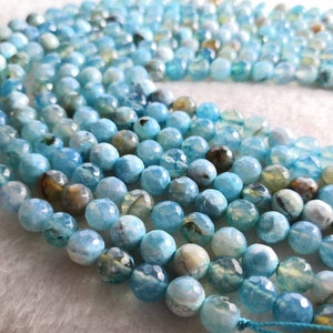 Può includere: Primo piano di fili di perline sfaccettate rotonde nei toni dell'azzurro, dell'acqua marina e del marrone. Le perline hanno un aspetto lucido, adatte per la creazione di gioielli o lavori artigianali.