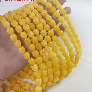 Op de afbeelding: Een streng gele bloemvormige kralen, elke kraal meet 8x12mm. De kralen zijn aan elkaar geregen op een doorzichtige draad en zijn spiraalvormig gerangschikt.