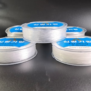 May include: Four spools of clear elastic string, each labeled "PU String 0.8mm Made in Korea" in blue and white text.