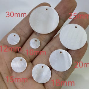 May include: Assortment of white mother of pearl round discs with holes for hanging. The discs range in size from 10mm to 30mm.