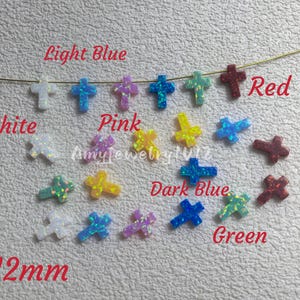Könnte beinhalten: Eine Sammlung kleiner kreuzförmiger Anhänger in verschiedenen Farben wie Weiß, Hellblau, Pink, Dunkelblau, Grün, Gelb und Rot. Die Anhänger messen 9x12mm und sind mit Textbeschriftungen versehen, die die Farben und den Namen Amyjewelry1012 angeben.