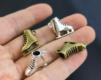 Puede incluir: Cuatro pequeños dijes de metal con forma de patines de hielo, que incluyen dos con acabado en bronce antiguo y dos en tono plateado brillante. Cada dije cuenta con una pequeña anilla en la parte superior para colgar, con detalles de cordones.