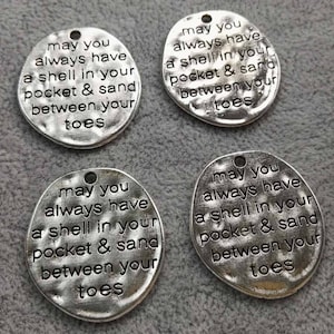 May include: Four silver charm pendants with the text "May you always have a shell in your pocket & sand between your toes" on each.