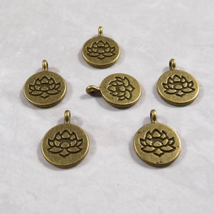 May include: Six antique gold-toned metal charms with a lotus flower design. Each charm has a loop for attaching to a necklace, bracelet, or other jewelry.