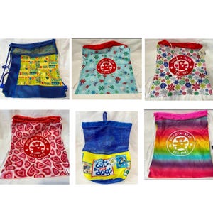 May include: A collection of six drawstring bags featuring various designs including Build-A-Bear logos, heart patterns, snowflake prints, rainbow gradients, and graphic text prints like Cool Cats & Hot Dogs, all with mesh or fabric construction.