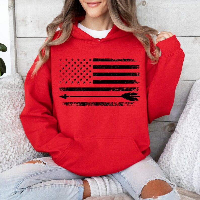 May include: Red hooded sweatshirt with a black and white distressed American flag design and an arrow with feathers.