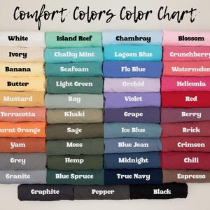 May include: A Comfort Colors color chart displaying a grid of folded fabric swatches in various shades. Each swatch is labeled with its corresponding color name, including White, Ivory, Banana, Butter, Mustard, Terracotta, Burnt Orange, Yam, Grey, Granite, Graphite, Island Reef, Chalky Mint, Seafoam, Light Green, Bay, Khaki, Sage, Moss, Hemp, Blue Spruce, Pepper, Chambray, Lagoon Blue, Flo Blue, Orchid, Violet, Grape, Ice Blue, Blue Jean, Midnight, True Navy, Blossom, Crunchberry, Watermelon, Heliconia, Red, Berry, Brick, Crimson, Chili, Espresso, and Black.