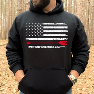 May include: Black hooded sweatshirt with a distressed white American flag and a red arrow across the center.