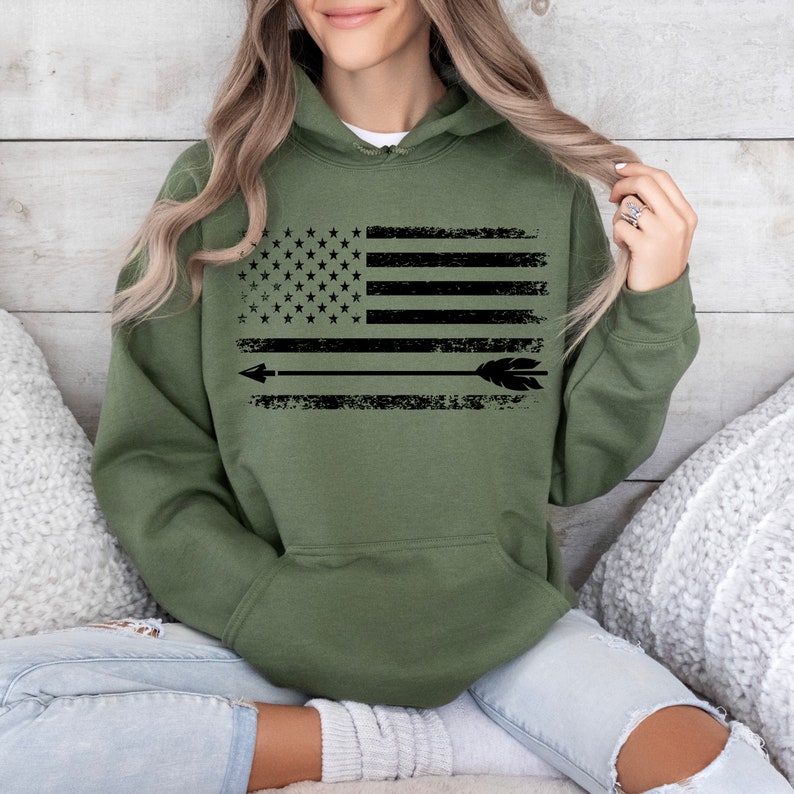 May include: A green hooded sweatshirt with a distressed black and white American flag design and a black arrow with a feather on the end.