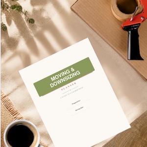 Op de afbeelding: Een witte papieren planner met de titel Moving & Downsizing Planner: A Guide to a Calmer Move. De omslag bevat een groen rechthoekig blok met witte tekst, gevolgd door de subtitel Planner en lege regels voor Prepared for en Moving date.