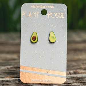 May include: A pair of avocado-shaped earrings on a white card with the text "Responsibly Made Plant Posse Hypoallergenic".