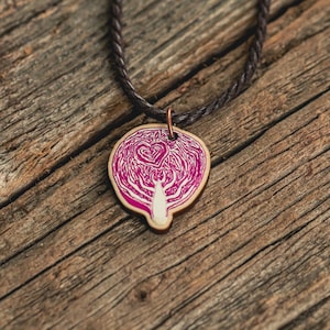 A necklace featuring an original painting of a halved cabbage with a small heart in it, printed on a die-cut wooden pendant. The cord is brown vegan-friendly waxed cotton.