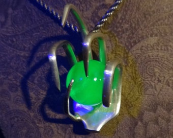 May include: A silver necklace with a green glass orb pendant held in a claw-like design.