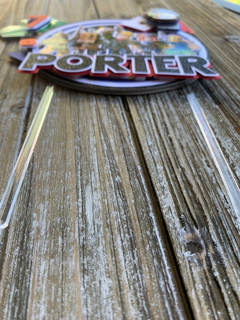 Pu&ograve; includere: Un topper per torta a pi&ugrave; livelli con un personaggio dei cartoni animati con il nome "Porter" in lettere rosse e nere. Il topper &egrave; decorato con una variet&agrave; di colori e disegni.