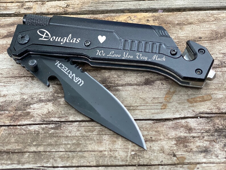 May include: Black multi-tool knife with a partially open blade. The knife has the name "Douglas", a heart symbol, and the phrase "We Love You Very Much" engraved on it. The knife also has a bottle opener and a seat belt cutter.