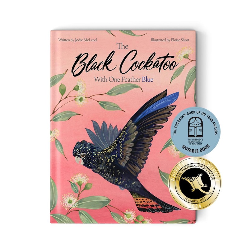 May include: The cover of a children's book titled "The Black Cockatoo with One Feather Blue". The cover features a colorful illustration of a black cockatoo with a blue wing, flying against a pink background with white flowers.