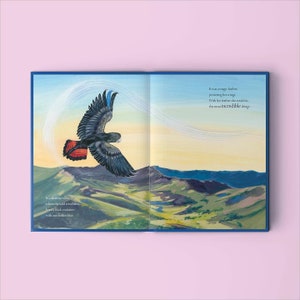 May include: A black cockatoo with a red tail flies through a valley with a blue feather. The text reads "It was a magic feather powering her wings. With her feather she could do the most incredible things..."