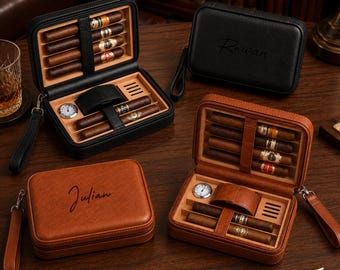 May include: Two rectangular cigar travel cases in black and tan leather, each featuring a cedar-lined interior with slots for cigars, a small round analog hygrometer, and a leather strap. The exterior lids are personalized with the names Rowan and Julian.