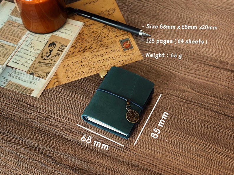 Może przedstawiać: Zielony notes sk&oacute;rzany z niebieskim sznurkiem i metalowym brelokiem. Notes ma wymiary 8,5 cm x 6,8 cm i grubość 2 cm. Zawiera 128 stron (64 arkuszy) i waży 65 gram&oacute;w.