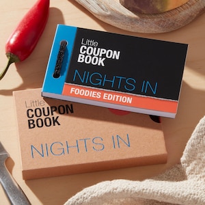 May include: Two "Little Coupon Book" notebooks. One has a black cover with "Nights In Foodies Edition" text. The other is tan with "Nights In" text. A red chili pepper and a knife are also visible.