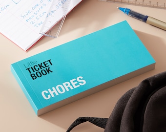 May include: A blue book with the title "Little Ticket Book" and the word "CHORES" in white letters. The book is on a light brown surface.