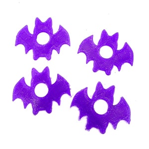 May include: Four purple plastic bat-shaped ornaments with a hole in the center.