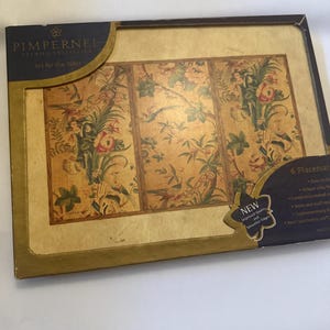 May include: A set of six placemats with a floral and bird design. The placemats are in a box with the brand name "Pimpernel" and the text "Art for the Table". The box has a gold border and a "NEW" sticker.
