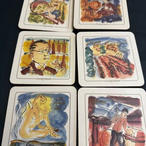 May include: Six square-shaped coasters with a white background and a colorful illustration on each. The illustrations depict different stages of winemaking, including harvest, blending, vineyards, the aging process, and the finished product. Each coaster has the word "COURVOISIER" printed in gold at the bottom.