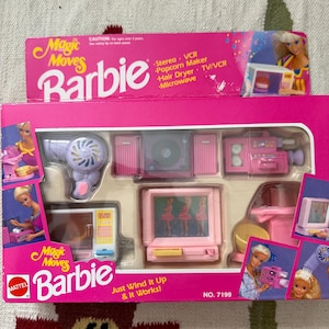 May include: A vintage Barbie Magic Moves playset in a pink box. The set includes miniature appliances like a hair dryer, TV, microwave, and stereo. The box features the Barbie logo and the text "Just Wind It Up & It Works!"