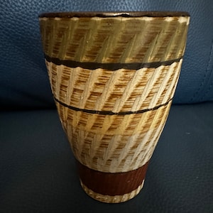 Può includere: Un vaso in ceramica marrone e beige con un motivo testurizzato. Il vaso ha una base larga e un'apertura stretta.