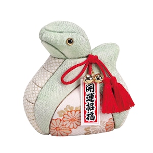May include: A green and white fabric turtle with a red string and tassels. The turtle has a tag that says "招運招福" in black text.