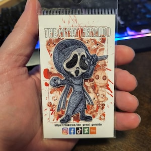 Könnte beinhalten: Ein blauer und weißer gestickter Aufnäher mit einem Cartoon-Geist, der ein Messer hält. Der Aufnäher ist von einem roten und weißen Hintergrund mit anderen Cartoon-Charakteren umgeben. Der Text "THE GREAT GERALDO" befindet sich oben auf dem Aufnäher. Der Text "https://linktr.ee/the_great_geraldo" befindet sich unten auf dem Aufnäher. Social-Media-Icons für Instagram, Facebook, TikTok und Etsy sind ebenfalls enthalten.