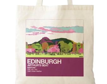 May include: A cream-colored canvas tote bag featuring a rectangular graphic print of a landscape with a hill, trees, and a sky. The text reads EDINBURGH, ARTHUR'S SEAT, EDOTONE, 2008-822-AUH, and Auld Urban Heather in white and dark purple.