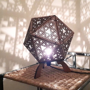 Table lamp in wood to be laid in platonic form with projection of geometric shapes in fractal Sierpiński laser cutting