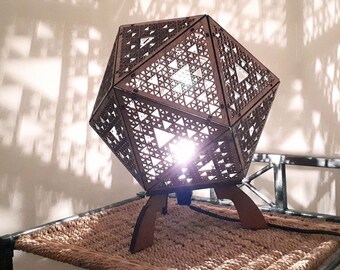 Table lamp in wood to be laid in platonic form with projection of geometric shapes in fractal Sierpiński laser cutting