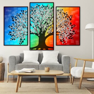 Puede incluir: Un tr&iacute;ptico de impresiones art&iacute;sticas abstractas de &aacute;rboles. Cada lienzo enmarcado presenta una silueta de &aacute;rbol con detalles florales blancos sobre un fondo degradado de azul, verde y rojo. La obra de arte se exhibe sobre un sof&aacute; gris.
