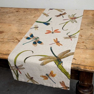 Peut inclure: Un chemin de table en lin beige avec un motif de libellules. Les libellules sont de différentes nuances de bleu, vert, orange et marron. Le chemin de table mesure environ 35,5 cm de large et 183 cm de long.