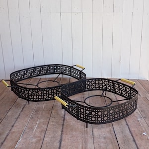 May include: Two black metal roasting racks with gold handles. The racks are oval and square shaped and have a decorative pattern of small circles.