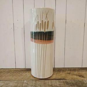 May include: A white ceramic vase with a brown and orange striped design and a pattern of brown reeds.