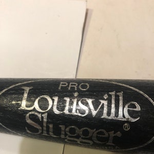 May include: Close-up of a black baseball bat with a silver "Louisville Slugger" logo and "PRO" written above it.