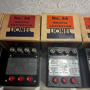 Puede incluir: Controlador de silbato Lionel No. 66 vintage, con cajas originales. Las cajas tienen etiquetas rojas y naranjas. Los controladores son negros con botones rojos y texto plateado. El texto del controlador dice "Whistle Controller No. 66".