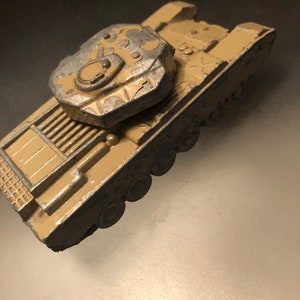May include: A toy tank in a camouflage color scheme. The tank is made of metal and has a detailed design. The tank is in good condition, with some wear and tear.