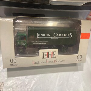 May include: A green toy truck model of a London Carriers delivery truck. The truck has the words "London Carriers Limited" on the side. The truck is a 1/76 scale model and is part of the EFE Exclusive First Editions series.