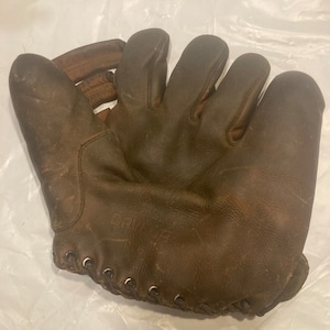 May include: A brown leather baseball glove with laces. The glove is worn and has a vintage look.